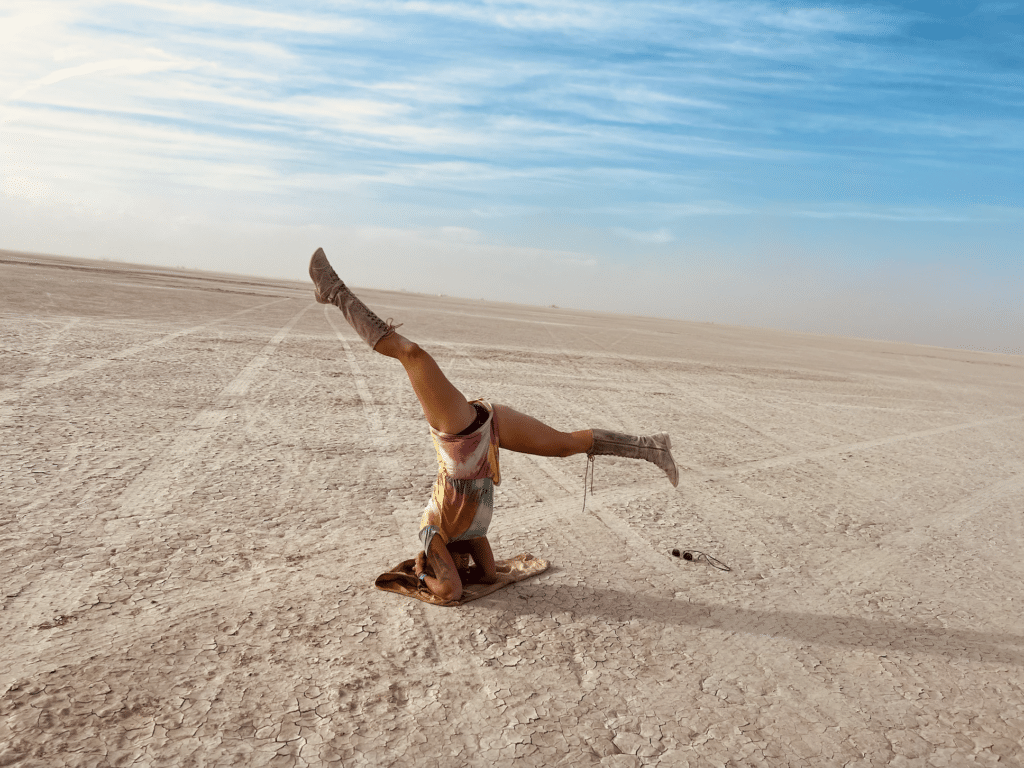 Woman does a headstand on the empty playa at Burning Man.